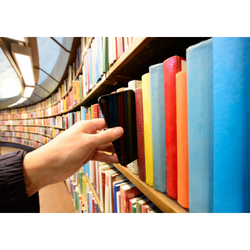A hand reaches into a library shelf of colourful books and takes out a cell phone