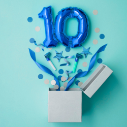 balloons in the shape of the number 10 appear to explode out of a box followed by confetti and streamers.