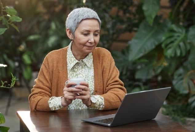 elderly woman smiling and using computer