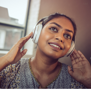 Close up of a woman with brown skin wearing headphones and smiling. 