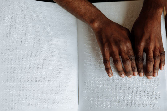 A pair of hands read a braille book.