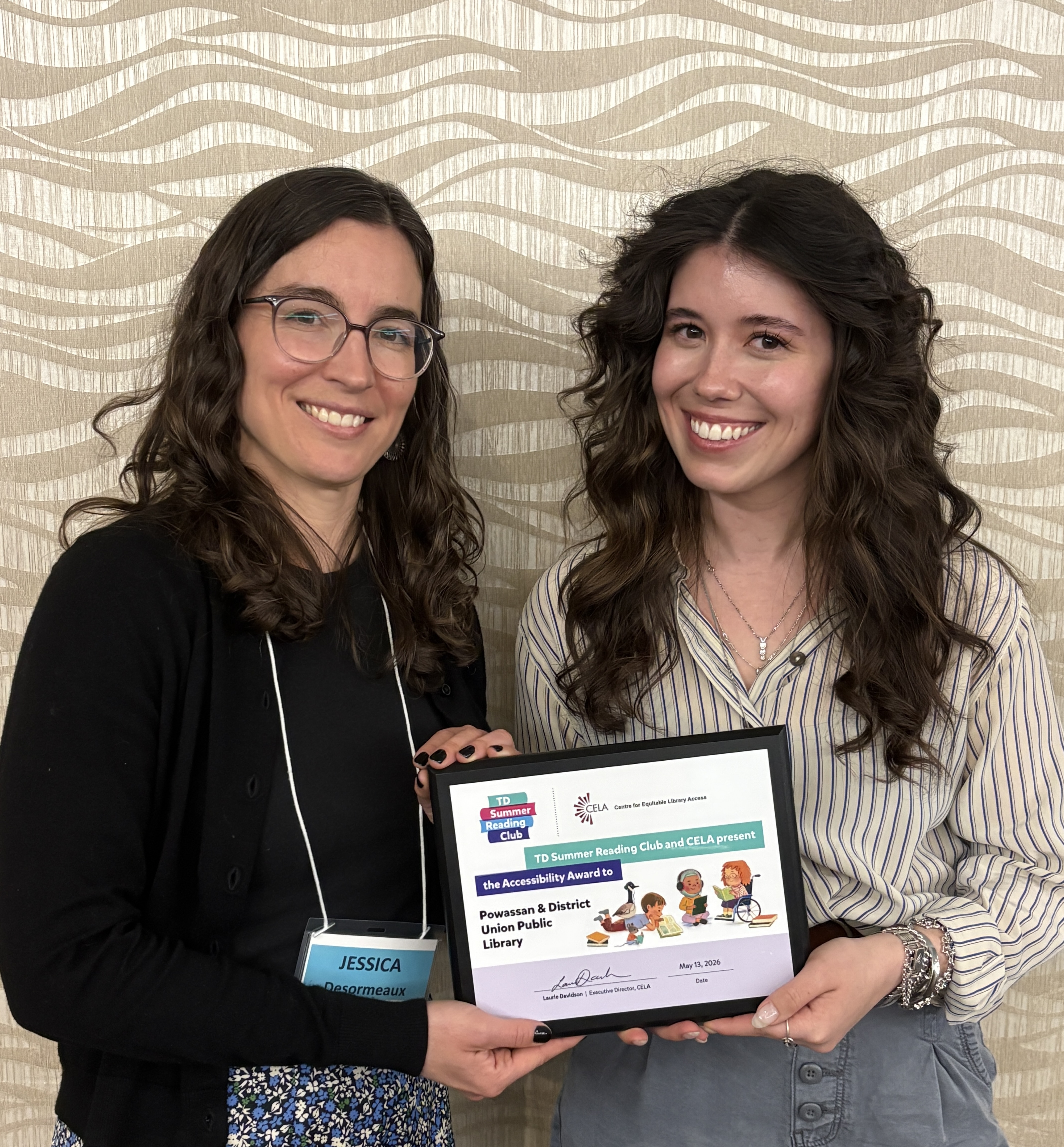 Jessica Desourmeaux from CELA stands beside Breya Market-Matthews, Communication and Program Coordinator from the Powassan Public Library. They are smiling at the camera and holding the plaque for the TDSRC Accessibility Award