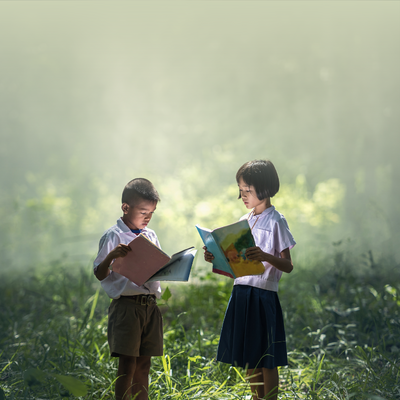 Deux enfants se tiennent dans les hautes herbes en train de lire des livres. Il y a du brouillard derrière eux.