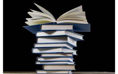 A stack of several books with the bottom edges of the books facing outward. The book on the top of the stack is lying open. The background is black.