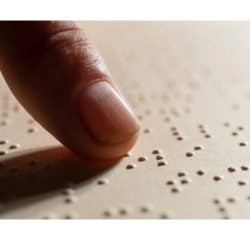 A finger moves across braille dots.