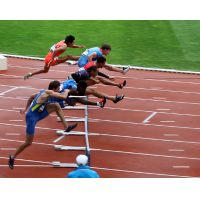 Men are jumping over hurdles as part of a race.
