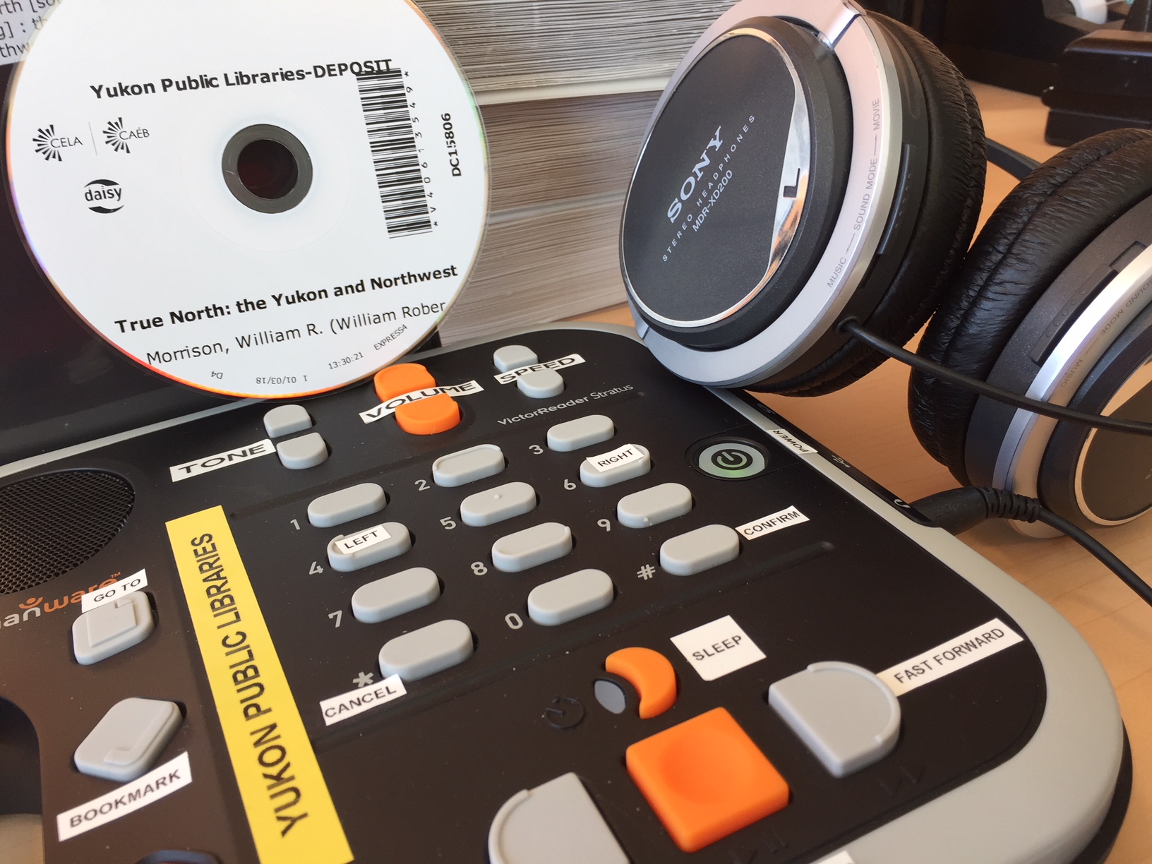 DAISY player, DAISY CD and headphones grouped together on a table.