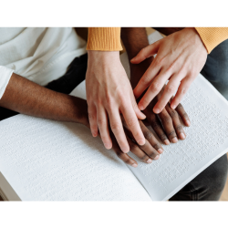 Two pair of hands read a braille book together. 