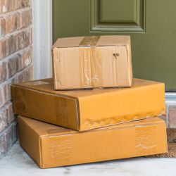a stack of three packages sits outside a green door