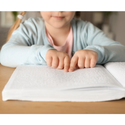 a young child reads a braille book at a table. 