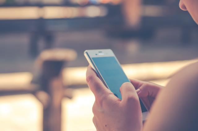 Close-up of a woman's hands holding an iPhone with a blue screen