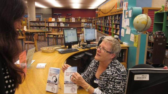 A librarian giving a patron a CELA handout