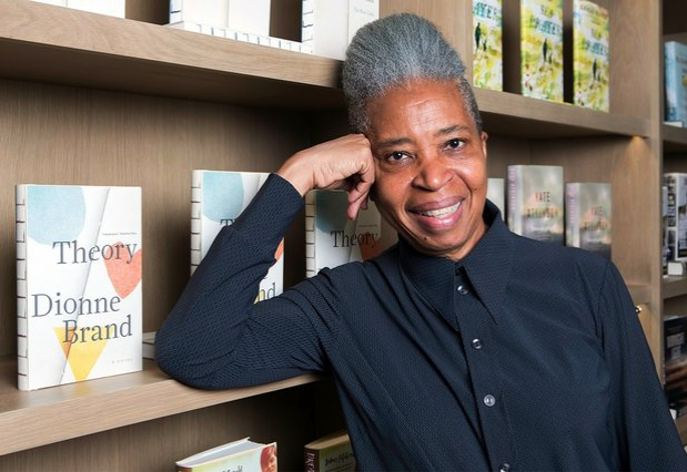 Photo of Dionne Brand standing next to a copy of Theory