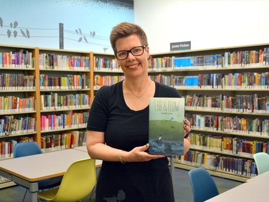 Picture of author holding their book Ebb and flow