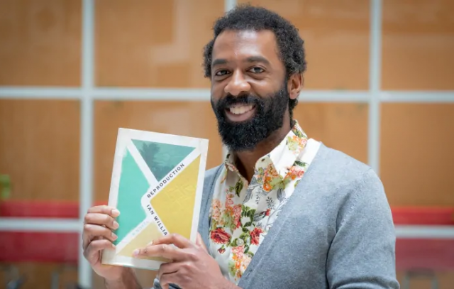 Photo of Iam Williams holding a copy of Reproduction